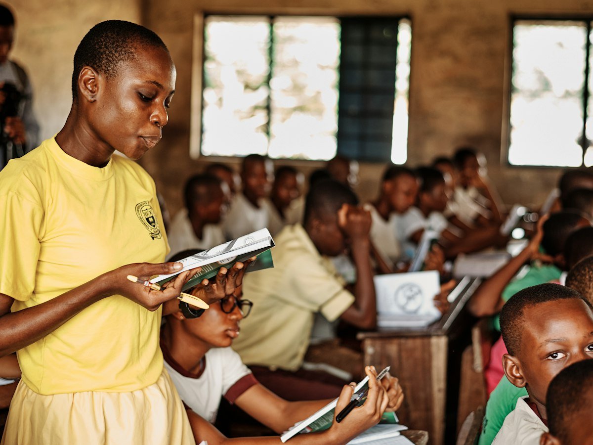 A teacher reading aloud to a full classroom of pupils