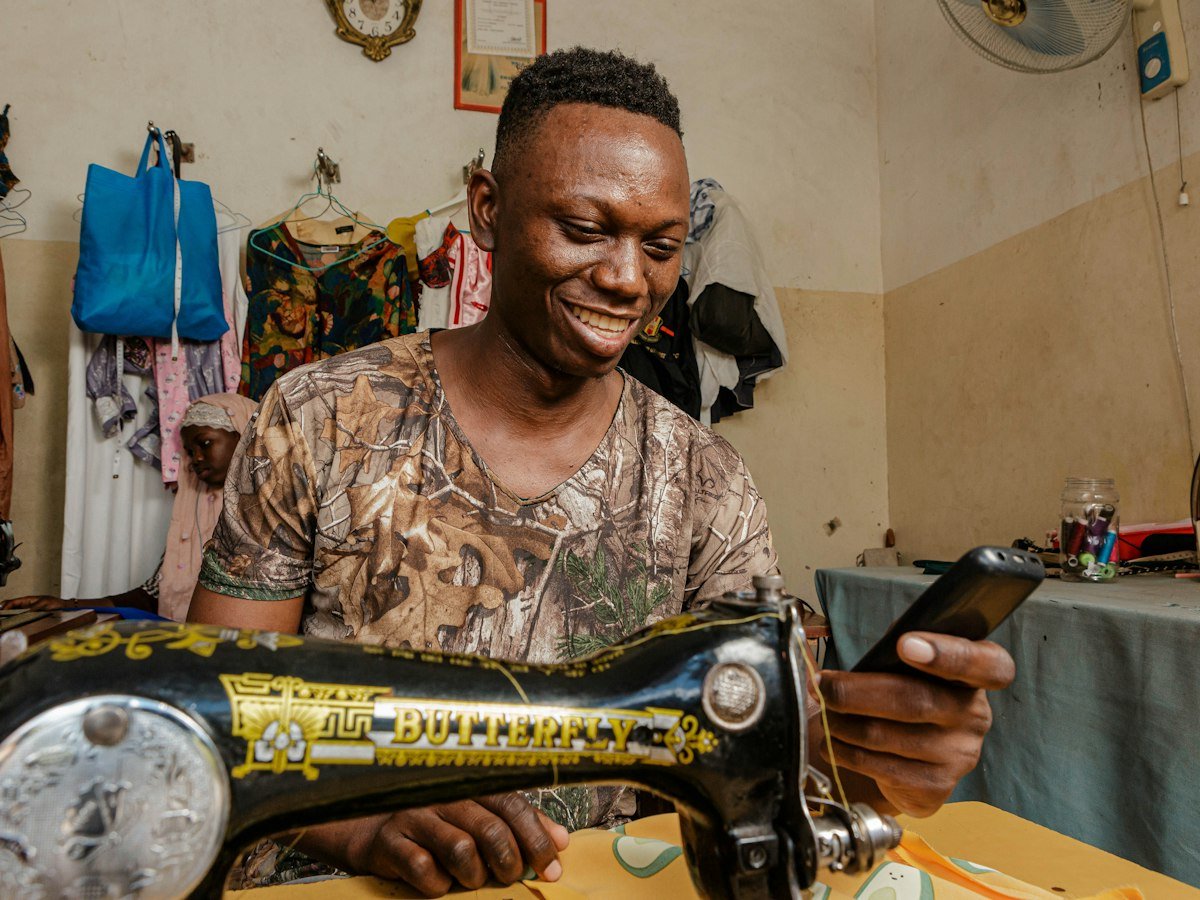 A smiling tailor working at his sewing machine in his shop