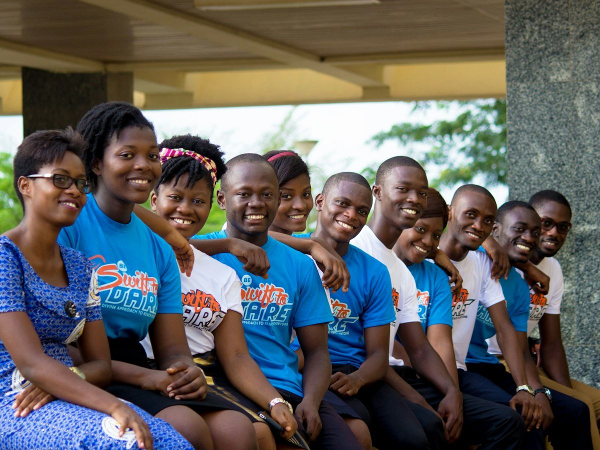 A group of young volunteers in matching T-shirts sitting together and smiling